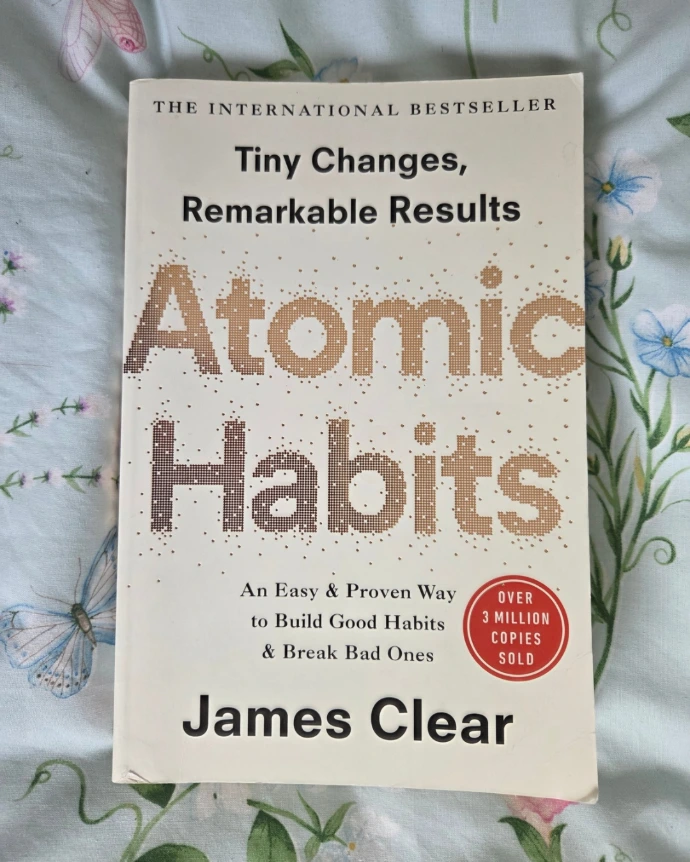 An image of the front cover of Atomic Habits by James Clear. A white background with Black and gold text